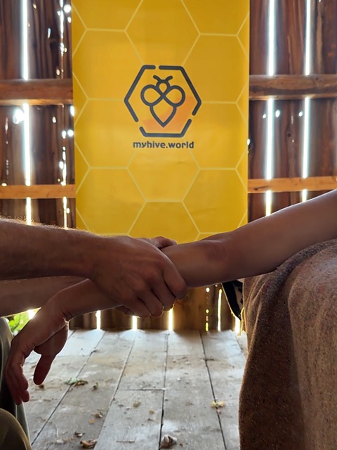 Two people holding forearms in front of the MyHive banner in a barn