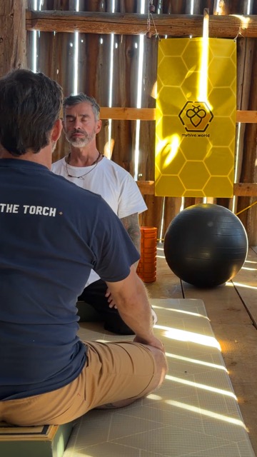 A Guide sitting with his eyes closed across from a man, the MyHive banner behind them